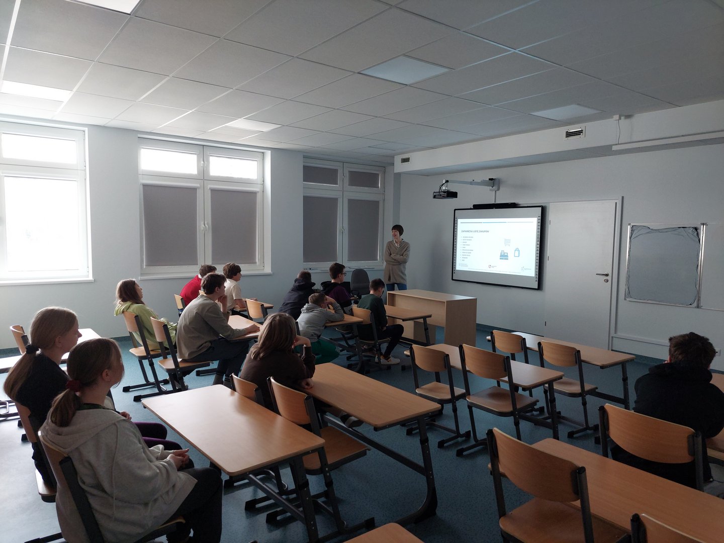 Dzieci siedzą w klasie i słuchają nauczyciela