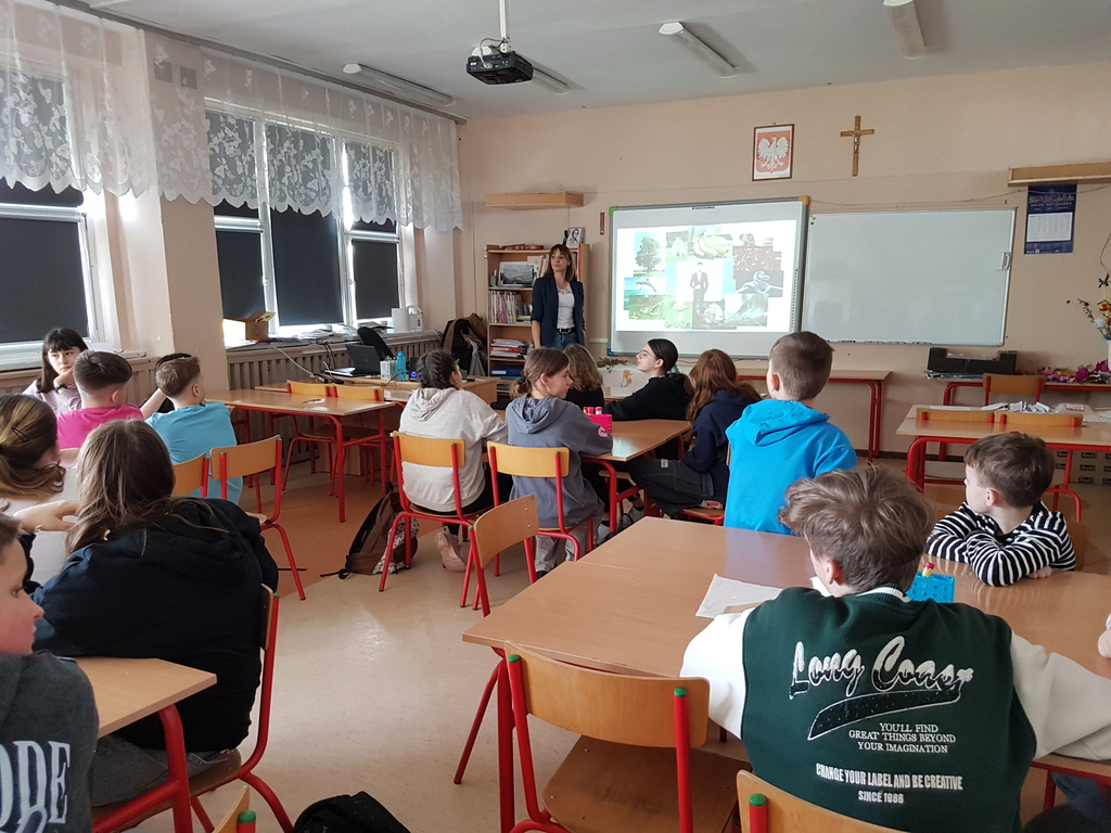 Dzieci w klasie słuchają wykładowcy, na ekranie widoczna komórka zwierzęca