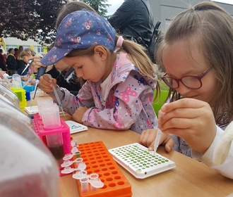 Dwie dziewczynki pipetują kolorowe płyny na pikniku