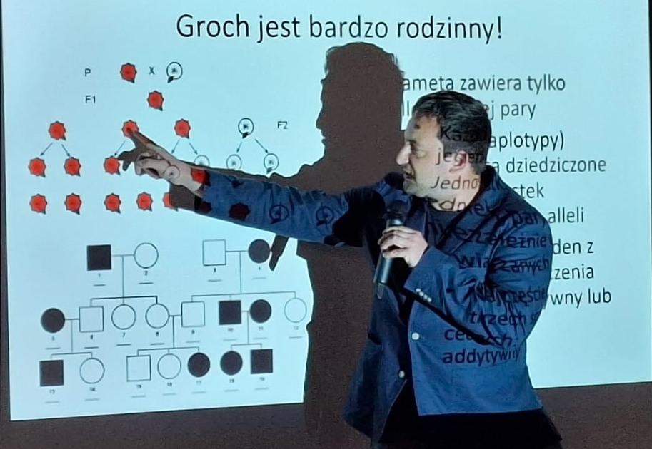 Wykładowca wskazuje ręką na omawiane szczegóły na talbicy interaktywnej