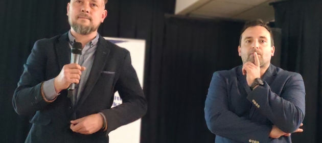 Dwaj wykładowcy słuchają pytań publiczności podczas prelekcji